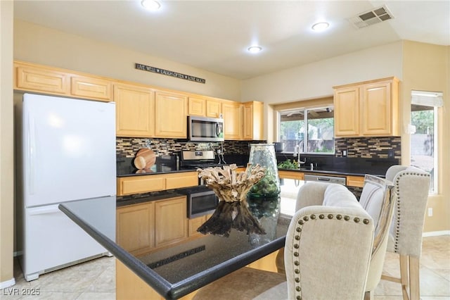 5434 Lost Ln, Las Vegas, NV 89118 - kitchen featuring appliances with stainless steel finishes, light brown cabinets, decorative backsplash, a center island, and a kitchen bar