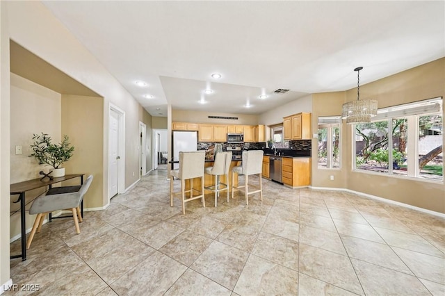 5434 Lost Ln, Las Vegas, NV 89118 - kitchen featuring stainless steel appliances, light brown cabinetry, a chandelier, backsplash, and a kitchen breakfast bar