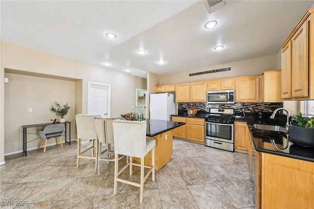 5434 Lost Ln, Las Vegas, NV 89118 - kitchen featuring appliances with stainless steel finishes, dark countertops, a breakfast bar, backsplash, and a center island