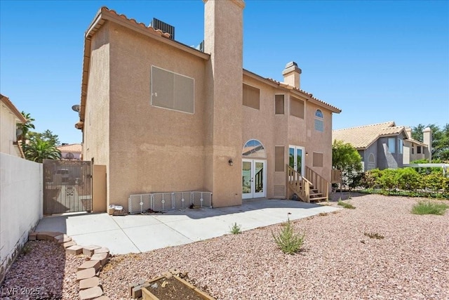 2842 Via Florentine St, Henderson, NV 89074 - back of property featuring a chimney, french doors, stucco siding, and a gate