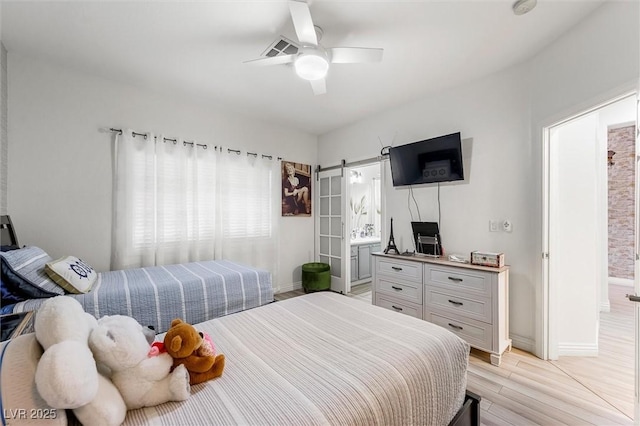 10372 Natural Springs Ave, Las Vegas, NV 89129 - bedroom featuring light wood-type flooring, a barn door, ceiling fan, and connected bathroom