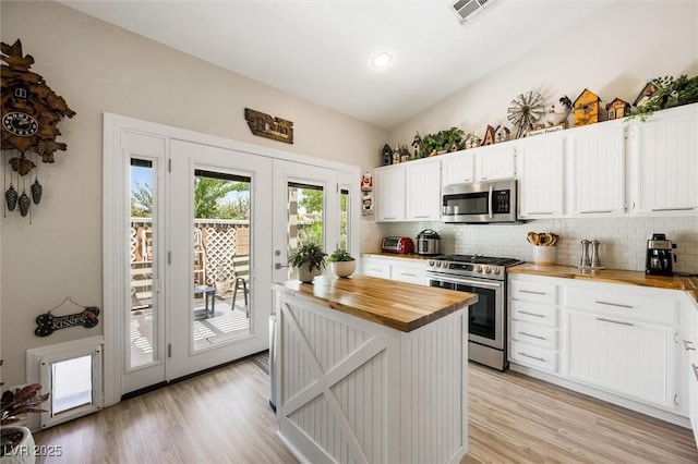 10372 Natural Springs Ave, Las Vegas, NV 89129 - kitchen featuring stainless steel appliances, butcher block countertops, decorative backsplash, light wood finished floors, and vaulted ceiling