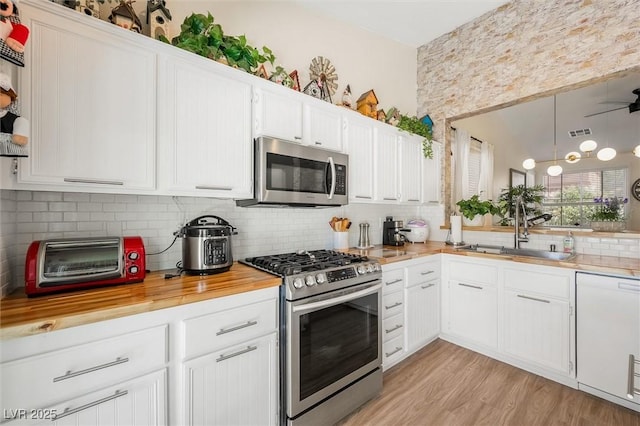 10372 Natural Springs Ave, Las Vegas, NV 89129 - kitchen featuring stainless steel appliances, tasteful backsplash, wooden counters, white cabinets, and light wood-style flooring