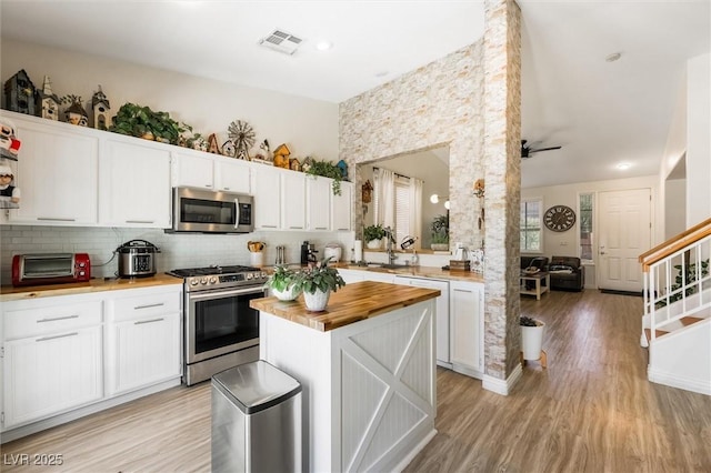 10372 Natural Springs Ave, Las Vegas, NV 89129 - kitchen with stainless steel appliances, butcher block counters, white cabinets, backsplash, and a towering ceiling
