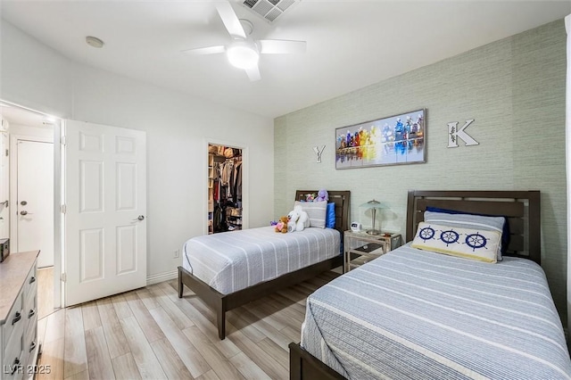 10372 Natural Springs Ave, Las Vegas, NV 89129 - bedroom with an accent wall, light wood finished floors, a walk in closet, and a ceiling fan
