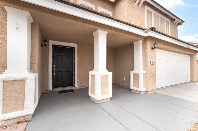 9578 Teton Vista Ave, Las Vegas, NV 89117 - view of exterior entry featuring an attached garage, stucco siding, driveway, and covered porch
