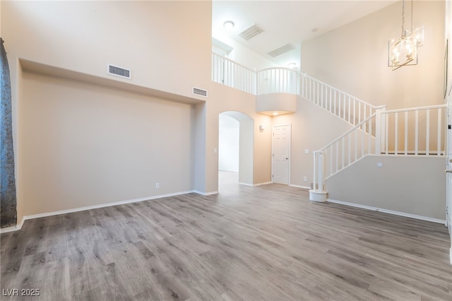 9578 Teton Vista Ave, Las Vegas, NV 89117 - unfurnished living room featuring wood finished floors, arched walkways, a high ceiling, and stairs