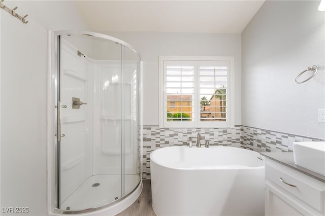 9578 Teton Vista Ave, Las Vegas, NV 89117 - bathroom featuring a stall shower, a freestanding bath, vanity, tile walls, and wood finished floors