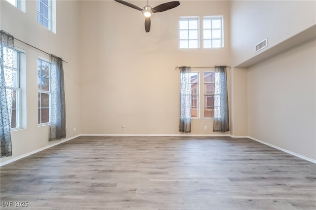 9578 Teton Vista Ave, Las Vegas, NV 89117 - empty room featuring a towering ceiling, wood finished floors, a ceiling fan, and plenty of natural light