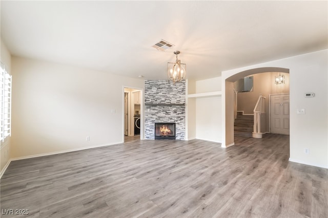 9578 Teton Vista Ave, Las Vegas, NV 89117 - unfurnished living room featuring a chandelier, stairs, wood finished floors, and arched walkways