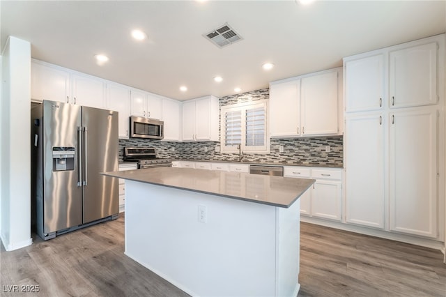 9578 Teton Vista Ave, Las Vegas, NV 89117 - kitchen with stainless steel appliances, wood finished floors, white cabinetry, a center island, and recessed lighting