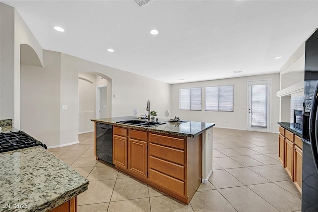 7558 Schuders Ave, Las Vegas, NV 89178 - kitchen with black appliances, arched walkways, light tile patterned floors, dark stone countertops, and recessed lighting