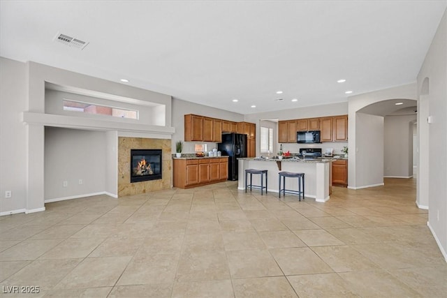 7558 Schuders Ave, Las Vegas, NV 89178 - kitchen with black appliances, recessed lighting, open floor plan, brown cabinetry, and light stone countertops