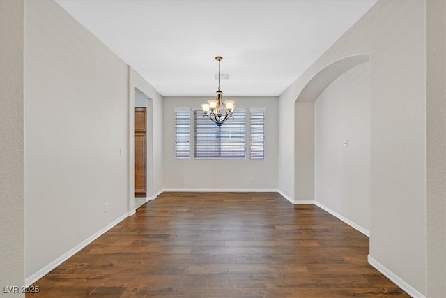 7558 Schuders Ave, Las Vegas, NV 89178 - unfurnished dining area featuring a chandelier, dark wood-type flooring, and arched walkways