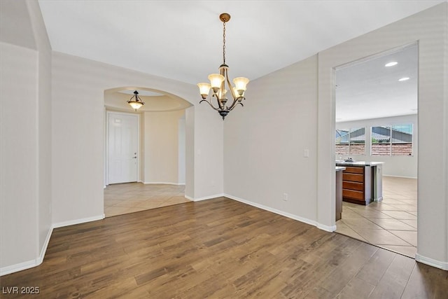7558 Schuders Ave, Las Vegas, NV 89178 - empty room with arched walkways, wood finished floors, a chandelier, and recessed lighting