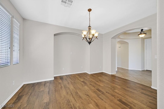 7558 Schuders Ave, Las Vegas, NV 89178 - empty room with arched walkways, wood finished floors, and a chandelier