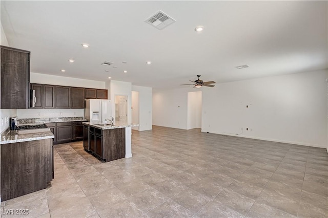 138 Red Sandstone Ave, North Las Vegas, NV 89031 - kitchen with white refrigerator with ice dispenser, ceiling fan, dark brown cabinets, a center island with sink, and open floor plan