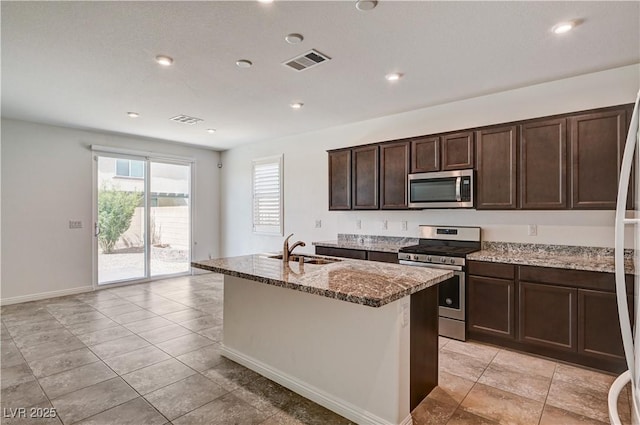 138 Red Sandstone Ave, North Las Vegas, NV 89031 - kitchen featuring appliances with stainless steel finishes, stone counters, an island with sink, dark brown cabinetry, and recessed lighting