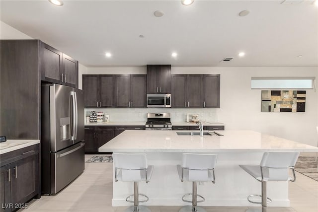 3244 Timorasso Ave, Henderson, NV 89044 - kitchen with stainless steel appliances, a breakfast bar area, dark brown cabinetry, a center island with sink, and recessed lighting