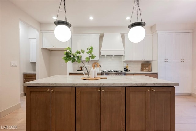 516 Pinnacle Heights Ln, Las Vegas, NV 89144 - kitchen featuring premium range hood, white cabinetry, an island with sink, backsplash, and decorative light fixtures