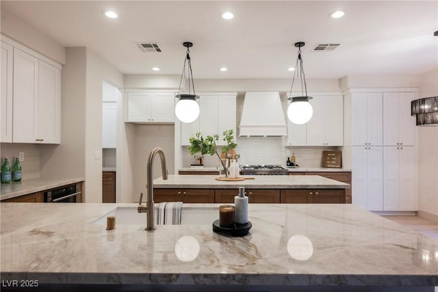 516 Pinnacle Heights Ln, Las Vegas, NV 89144 - kitchen featuring custom exhaust hood, backsplash, white cabinets, recessed lighting, and light stone counters