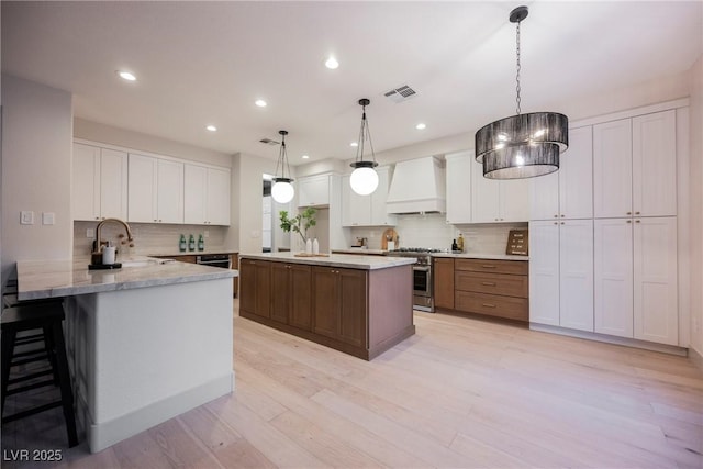516 Pinnacle Heights Ln, Las Vegas, NV 89144 - kitchen with custom range hood, high end stainless steel range oven, tasteful backsplash, white cabinets, and recessed lighting