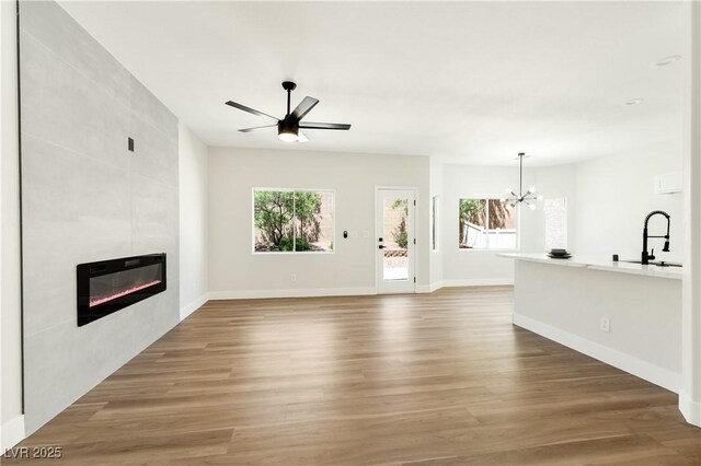 9349 Lakefront Color St, Las Vegas, NV 89178 - unfurnished living room with a chandelier, healthy amount of natural light, a tiled fireplace, and wood finished floors
