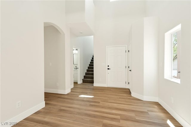 9349 Lakefront Color St, Las Vegas, NV 89178 - entrance foyer featuring arched walkways, stairs, light wood-type flooring, and a towering ceiling
