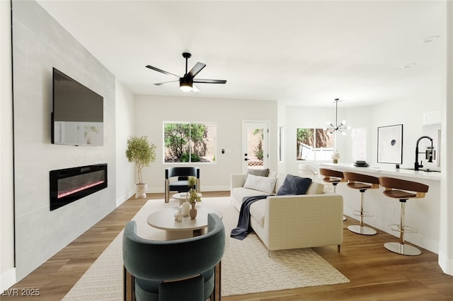 9349 Lakefront Color St, Las Vegas, NV 89178 - living area featuring a fireplace, wood finished floors, a chandelier, and a ceiling fan