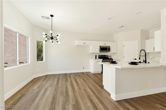 9349 Lakefront Color St, Las Vegas, NV 89178 - kitchen featuring stainless steel appliances, light wood-style flooring, white cabinetry, a chandelier, and light countertops