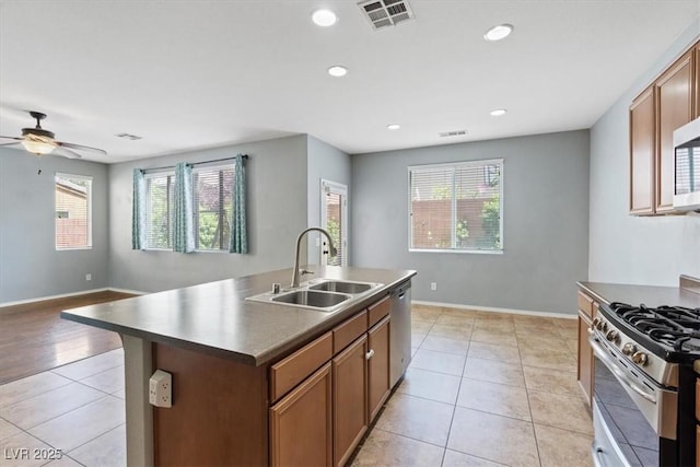 10645 Mount Jefferson Ave, Las Vegas, NV 89166 - kitchen with stainless steel appliances, light tile patterned floors, a ceiling fan, dark countertops, and a center island with sink