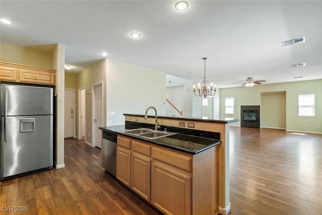 3613 Rubio Sun Ave, North Las Vegas, NV 89081 - kitchen with appliances with stainless steel finishes, a glass covered fireplace, dark wood-style floors, a chandelier, and a kitchen island with sink