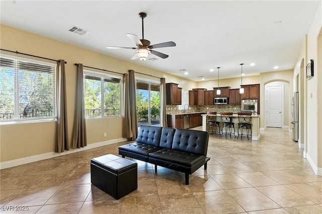 7330 Silent Water Way, Las Vegas, NV 89149 - living room featuring a ceiling fan, plenty of natural light, light tile patterned floors, arched walkways, and recessed lighting