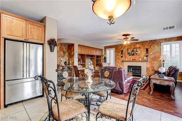 109 N Buteo Woods Ln, Las Vegas, NV 89144 - dining space with light tile patterned floors, ceiling fan, a glass covered fireplace, and arched walkways