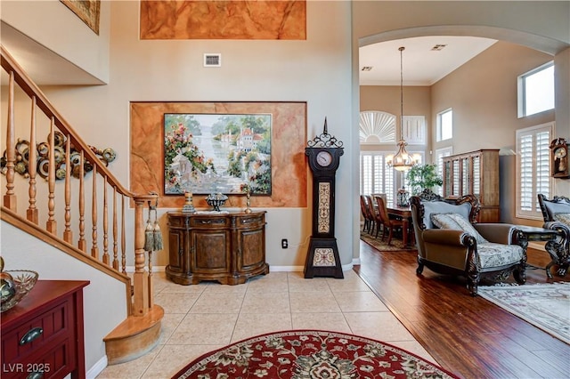 109 N Buteo Woods Ln, Las Vegas, NV 89144 - foyer entrance featuring arched walkways, a high ceiling, a chandelier, stairway, and light tile patterned floors
