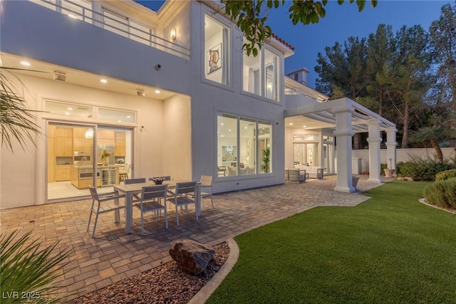 1613 Iron Ridge Dr, Las Vegas, NV 89117 - back of house at twilight with a balcony, a lawn, a patio, stucco siding, and outdoor dining space