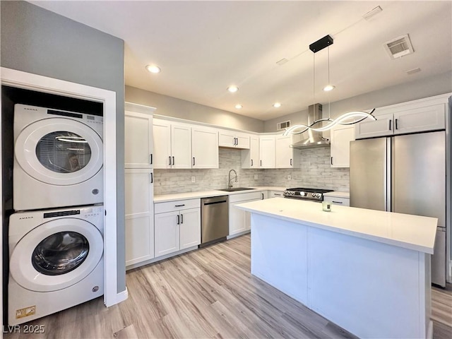 9000 Las Vegas Blvd Unit 1078, Las Vegas, NV 89123 - kitchen with stacked washer / dryer, appliances with stainless steel finishes, light countertops, white cabinets, and decorative backsplash