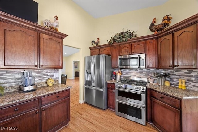 2408 Sunset Beach Ln, Las Vegas, NV 89128 - kitchen with appliances with stainless steel finishes, decorative backsplash, light wood-style flooring, and dark stone counters