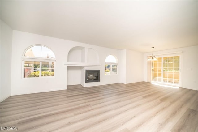 7950 W Flamingo Rd Unit 1009, Las Vegas, NV 89147 - unfurnished living room with a chandelier, light wood-style floors, and a glass covered fireplace