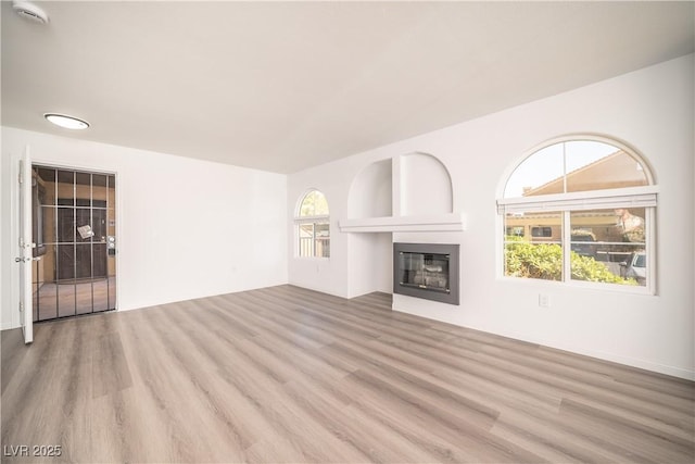 7950 W Flamingo Rd Unit 1009, Las Vegas, NV 89147 - unfurnished living room featuring wood finished floors and a glass covered fireplace