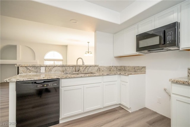 7950 W Flamingo Rd Unit 1009, Las Vegas, NV 89147 - kitchen with black appliances, light wood-style floors, light stone countertops, white cabinets, and a peninsula