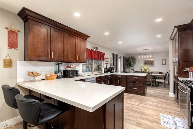 6457 Celeste Ave, Las Vegas, NV 89107 - kitchen featuring a peninsula, light countertops, stainless steel appliances, recessed lighting, and light wood-type flooring