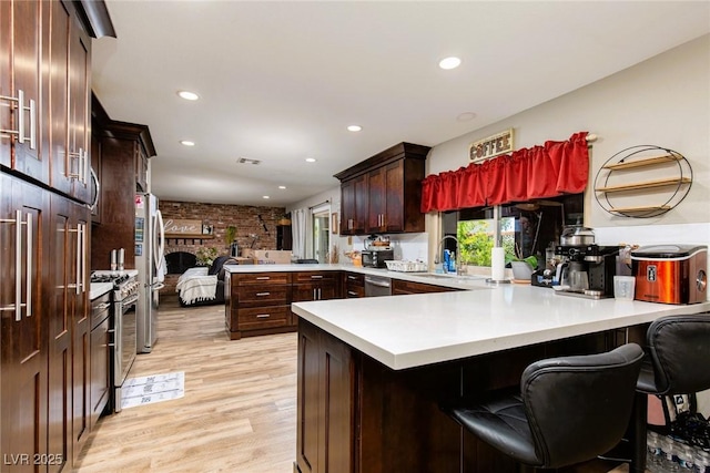 6457 Celeste Ave, Las Vegas, NV 89107 - kitchen with a peninsula, light wood finished floors, light countertops, recessed lighting, and dark brown cabinetry