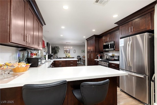 6457 Celeste Ave, Las Vegas, NV 89107 - kitchen with appliances with stainless steel finishes, a peninsula, light countertops, recessed lighting, and dark brown cabinets