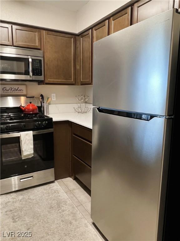 1420 Hialeah Dr Unit D, Las Vegas, NV 89119 - kitchen featuring appliances with stainless steel finishes, dark brown cabinets, light countertops, and light tile patterned floors