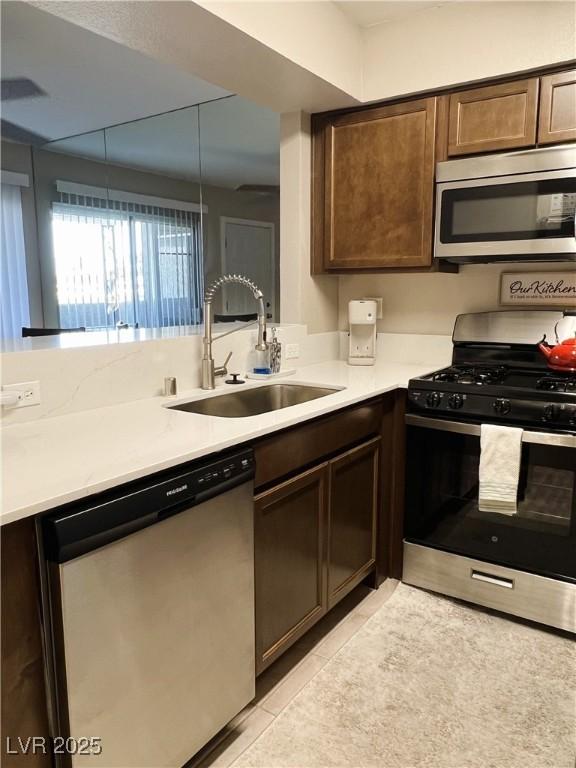 1420 Hialeah Dr Unit D, Las Vegas, NV 89119 - kitchen featuring stainless steel appliances, light tile patterned flooring, light countertops, and dark brown cabinetry