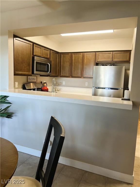 1420 Hialeah Dr Unit D, Las Vegas, NV 89119 - kitchen featuring stainless steel appliances, a peninsula, light countertops, and dark brown cabinets