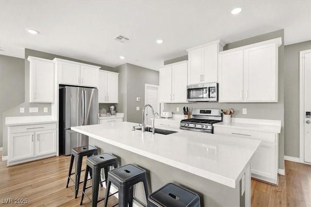 9835 Mojave Mountain St, Las Vegas, NV 89166 - kitchen featuring stainless steel appliances, a kitchen breakfast bar, white cabinets, light wood-style floors, and recessed lighting