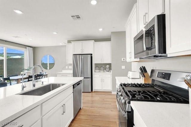9835 Mojave Mountain St, Las Vegas, NV 89166 - kitchen with appliances with stainless steel finishes, recessed lighting, white cabinetry, light wood-style flooring, and light stone countertops