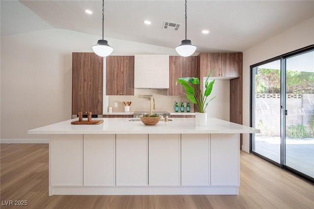 4594 Cabo Ln, Las Vegas, NV 89121 - kitchen with backsplash, modern cabinets, light wood-style flooring, lofted ceiling, and a spacious island
